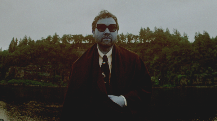 Artist Unknown Mortal Orchestra standing in front of a lake